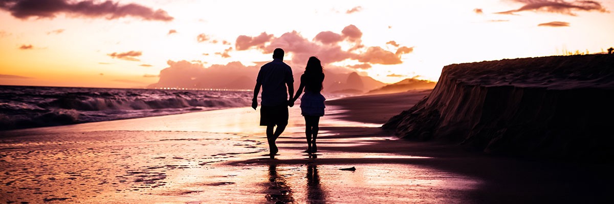 couple walking happily at seaside on sunset