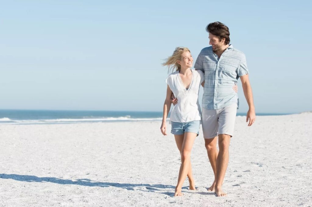 couple walking happily at seaside on sunset